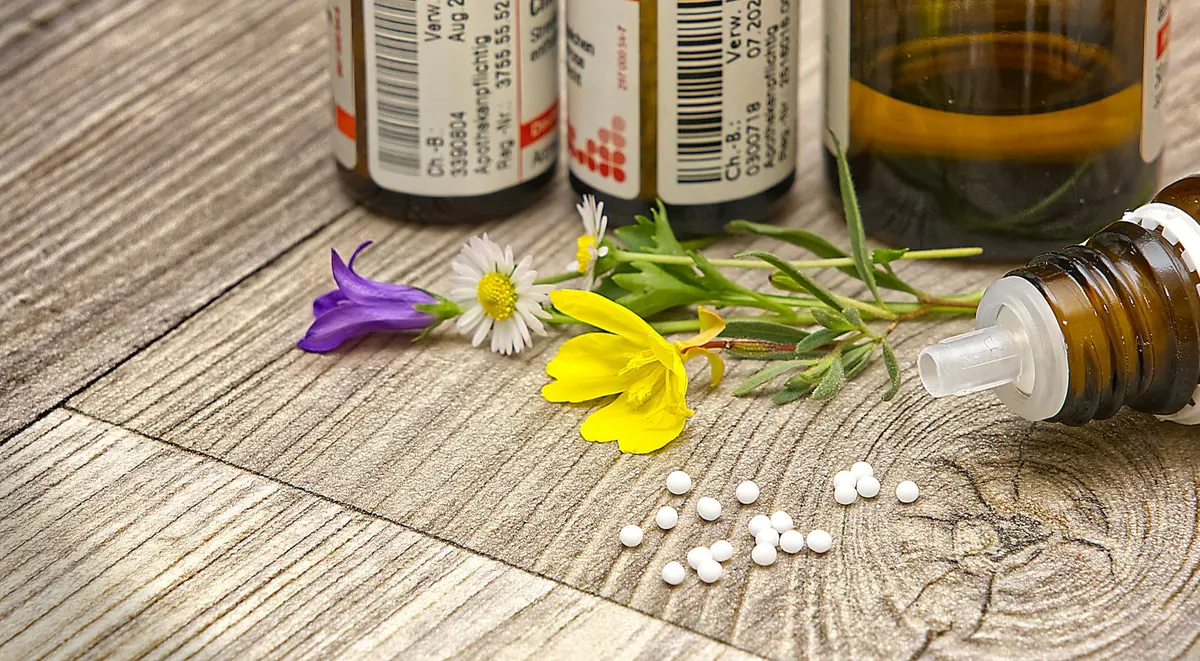 Homeopathic globules and remedy bottles on a wooden table